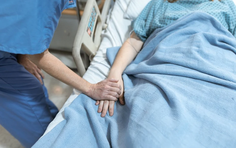 Care worker offering reassurance by holding a patient hand; illustrative stock photograph, not Formativelabz people or facilities