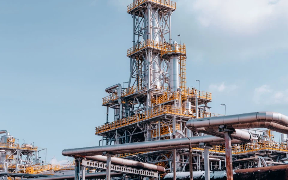 Refinery processing towers and pipelines under a blue sky; illustrative stock photograph, not Formativelabz people or facilities